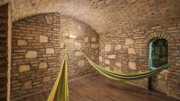 Une pièce avec un mur en briques, un hamac et un plancher en bois.
