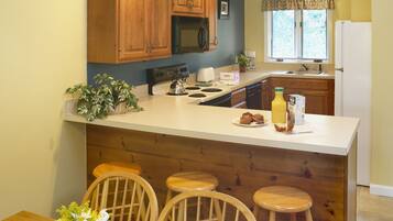 Una cocina compacta con armarios de madera, un microondas y un lavamanos.