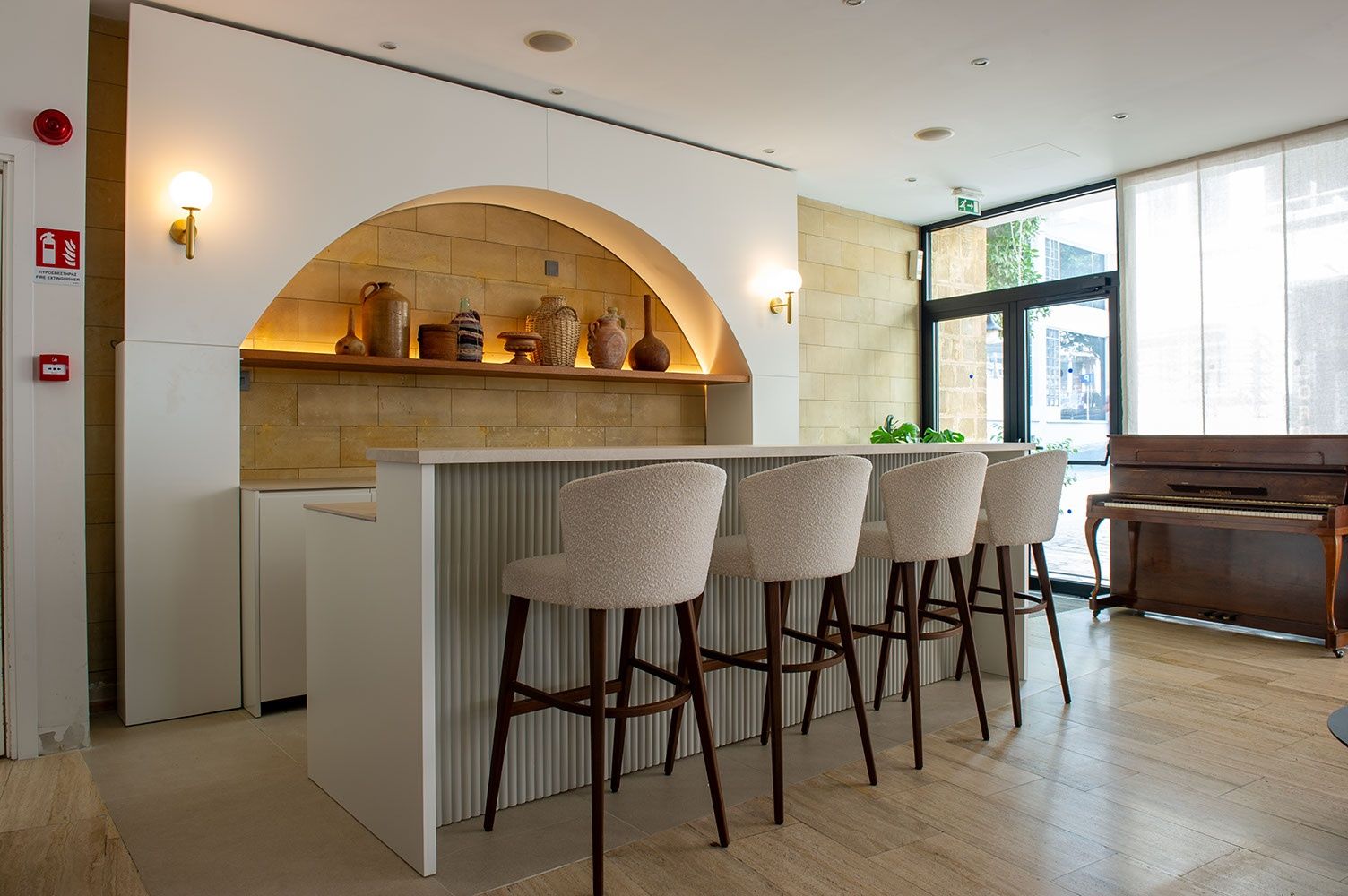 Una cocina moderna con barra integrada, revestimiento de piedra, taburetes de bar y un piano.