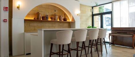 Una cocina moderna con barra integrada, revestimiento de piedra, taburetes de bar y un piano.