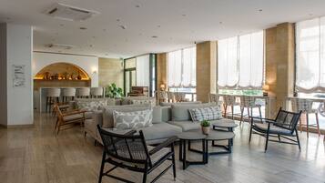 A spacious lounge area with seating arrangements, a fireplace, and large windows providing natural light.
