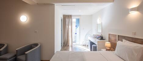 A hotel room with a bed, bedside table, lamp, and a view of the balcony.