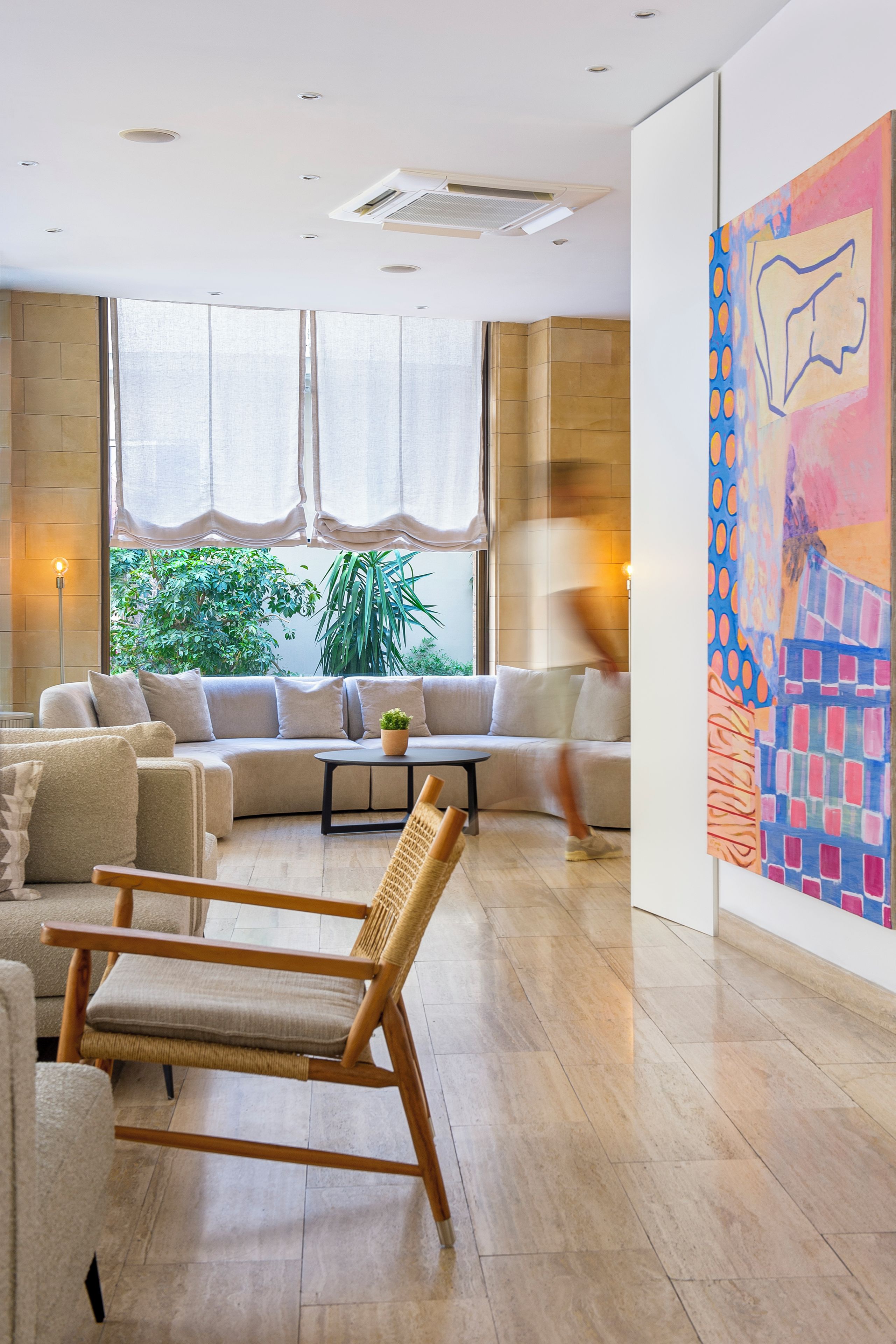 A modern living room with a sofa set, a wooden chair, and a large abstract painting on the wall.
