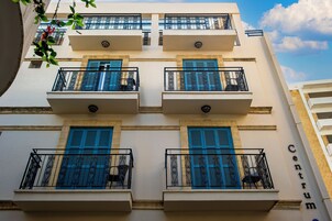 A building with multiple balconies, each with blue shutters and wrought iron railings.