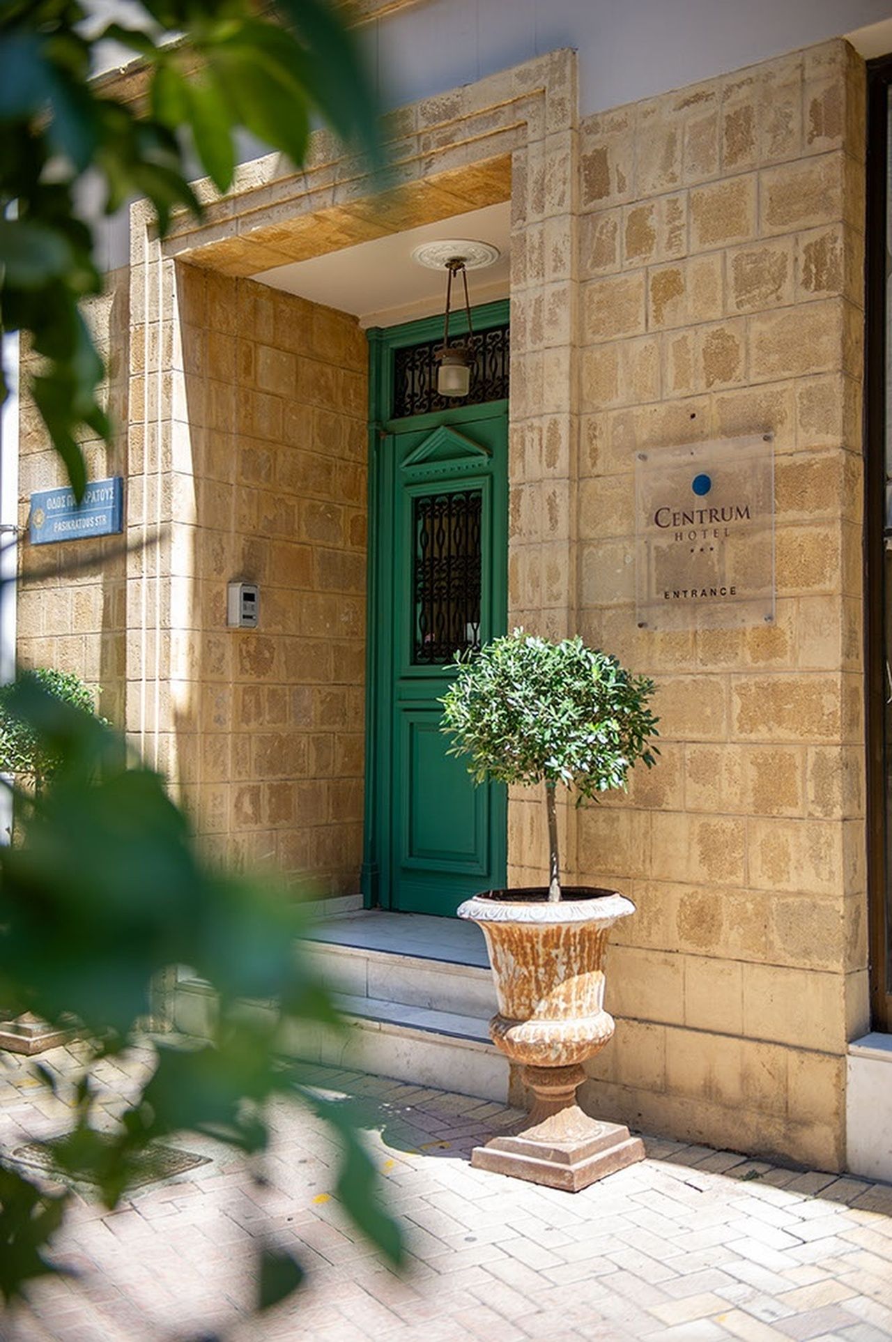 A stone building with a green door, a sign for 'Centrum Hotel', and a potted plant in front.