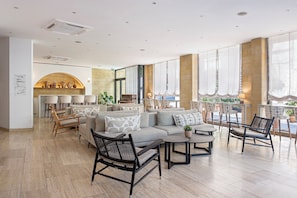 A spacious lounge area with a sofa, chairs, and tables, featuring a large arched window and a fireplace. - Centrum Hotel (Nicosia)