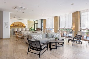 Amplia sala de estar con sofá, sillones y mesas, que cuenta con un gran ventanal de arco y una chimenea.