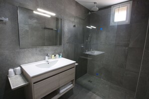 A modern bathroom with a large mirror, a white sink, and a glass-enclosed shower area.