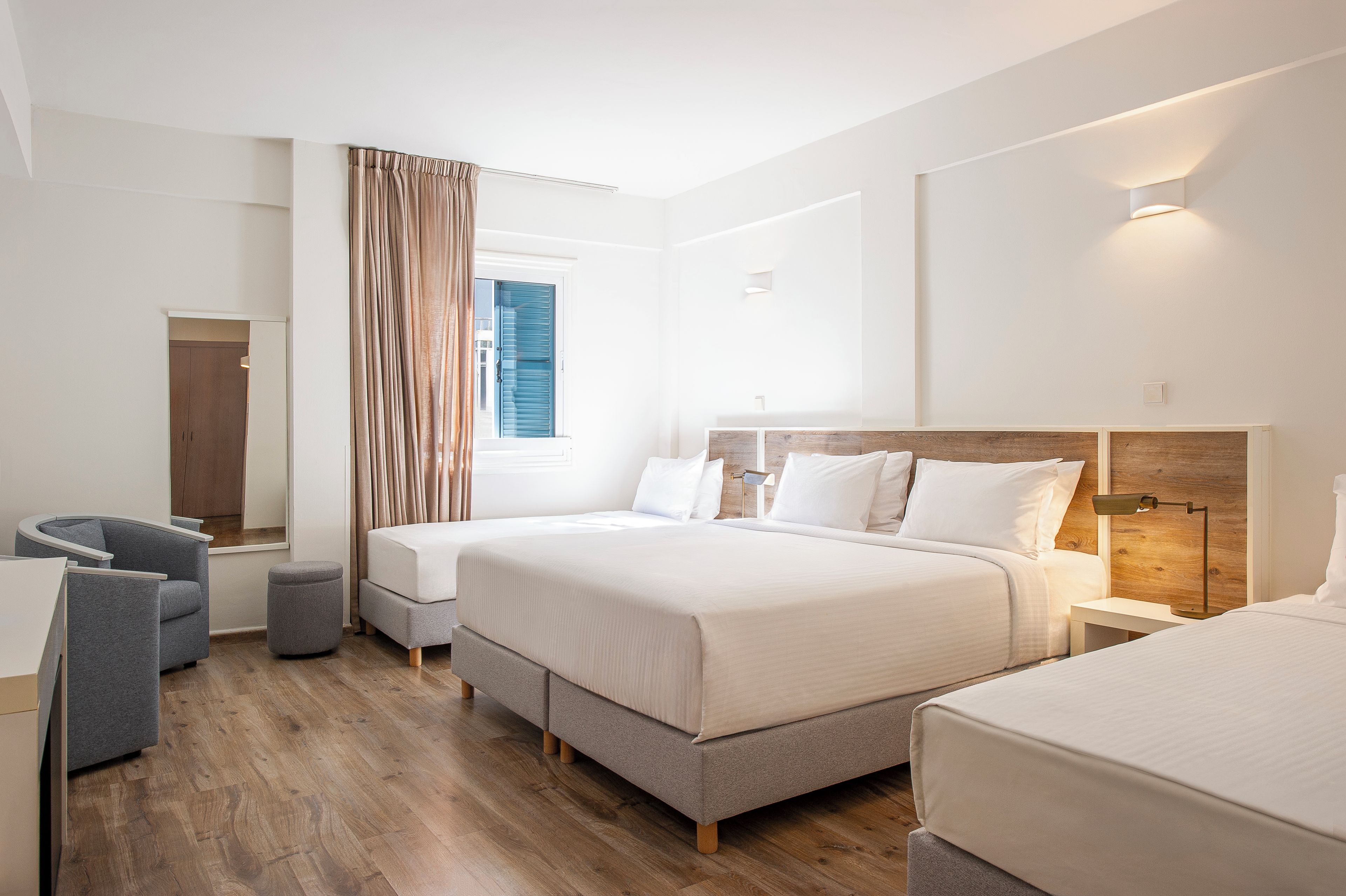 A modern hotel room with a large bed, a desk, and a chair.