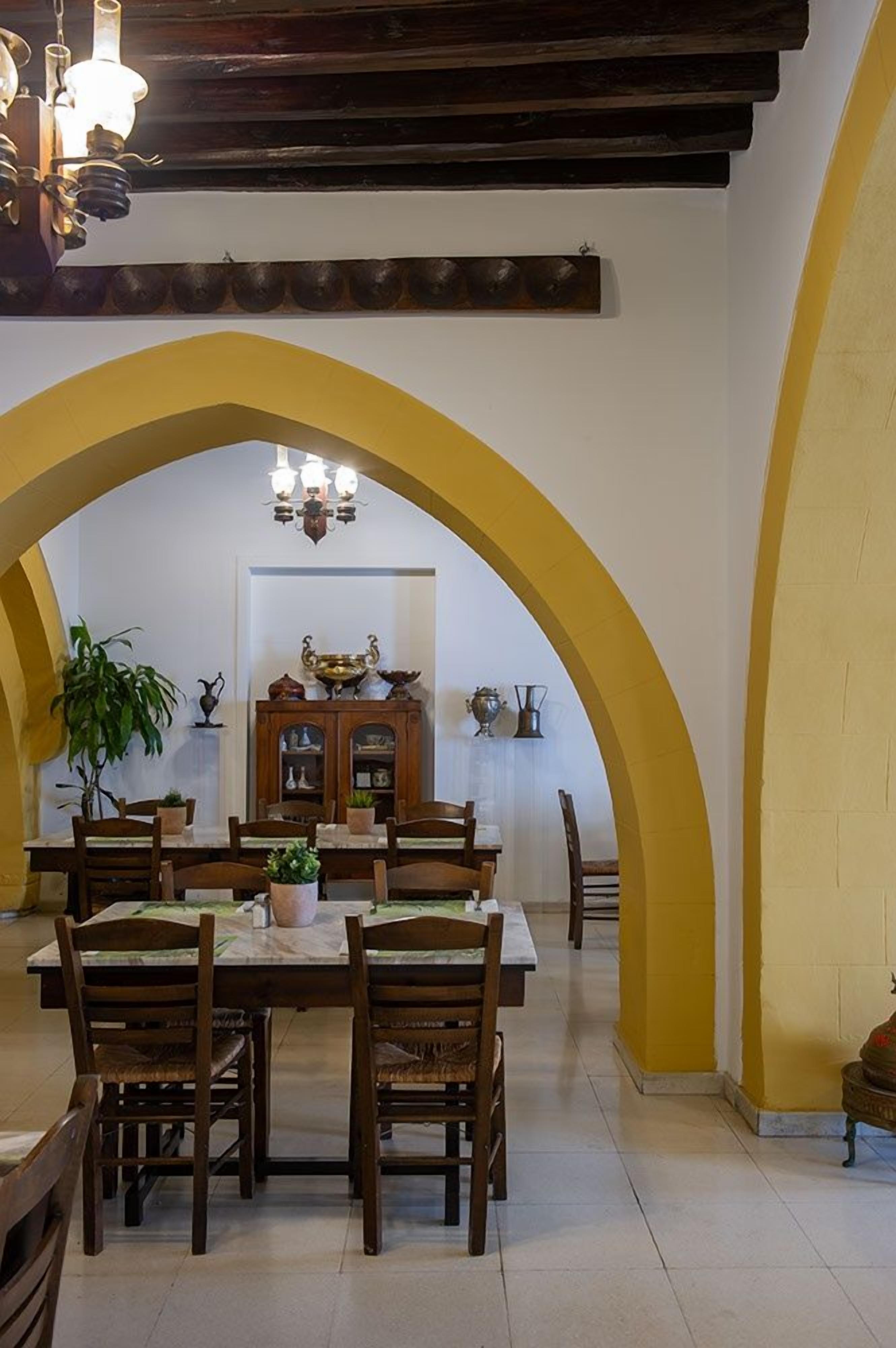 A dining area with a table set for six, surrounded by wooden chairs, under a vaulted ceiling with exposed beams.
