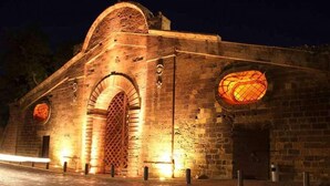 Un bâtiment historique doté d’une grande entrée en arc de cercle et de deux fenêtres circulaires illuminées.