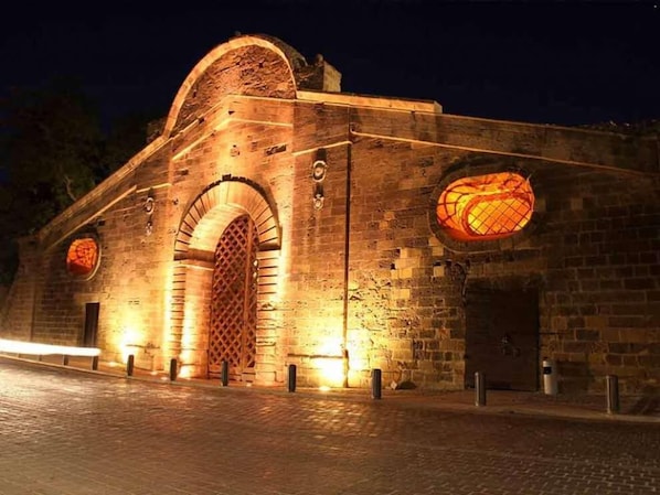 Um edifício histórico com uma grande entrada em arco e duas janelas circulares iluminadas.