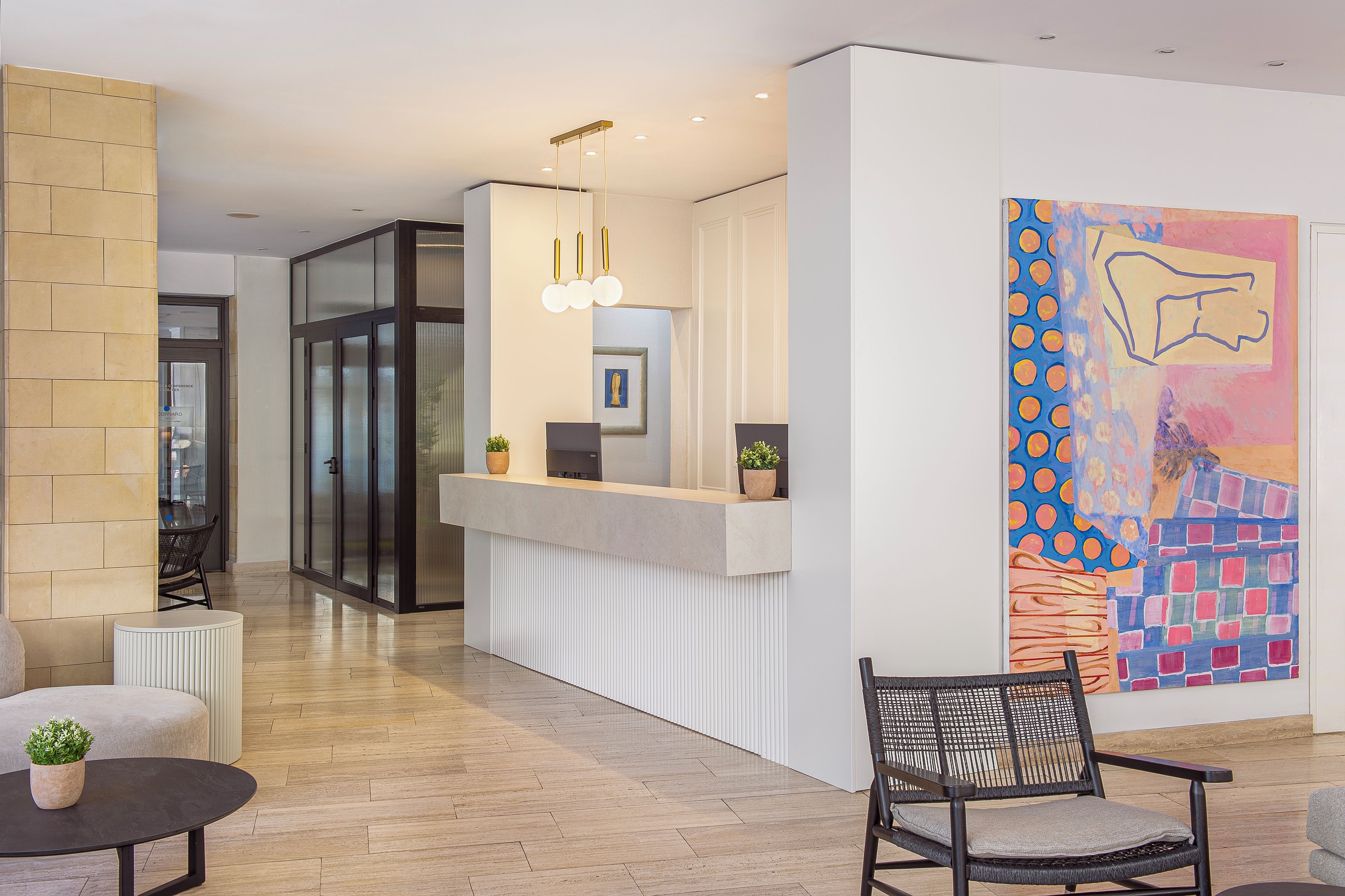 A reception area with a reception desk, seating, and a large abstract painting on the wall.