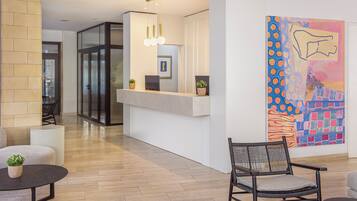A reception area with a reception desk, seating, and a large abstract painting on the wall.