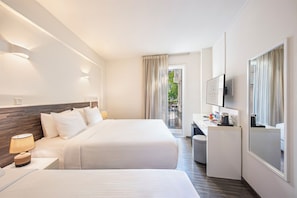 A hotel room with two beds, a desk, a TV, and a view of the outdoors. - Centrum Hotel (Nicosia)