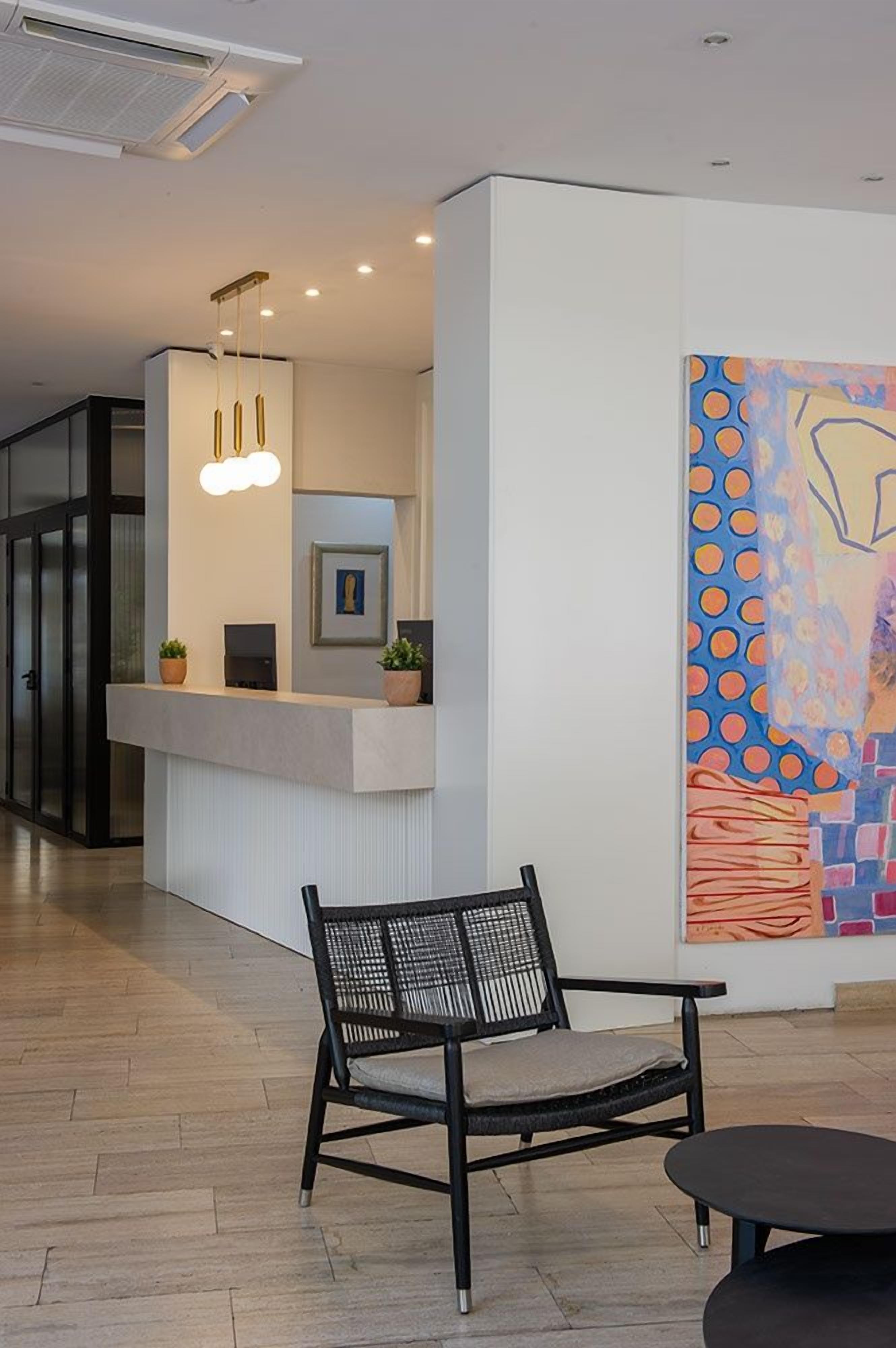 A reception area with a counter, a chair, and a painting on the wall.