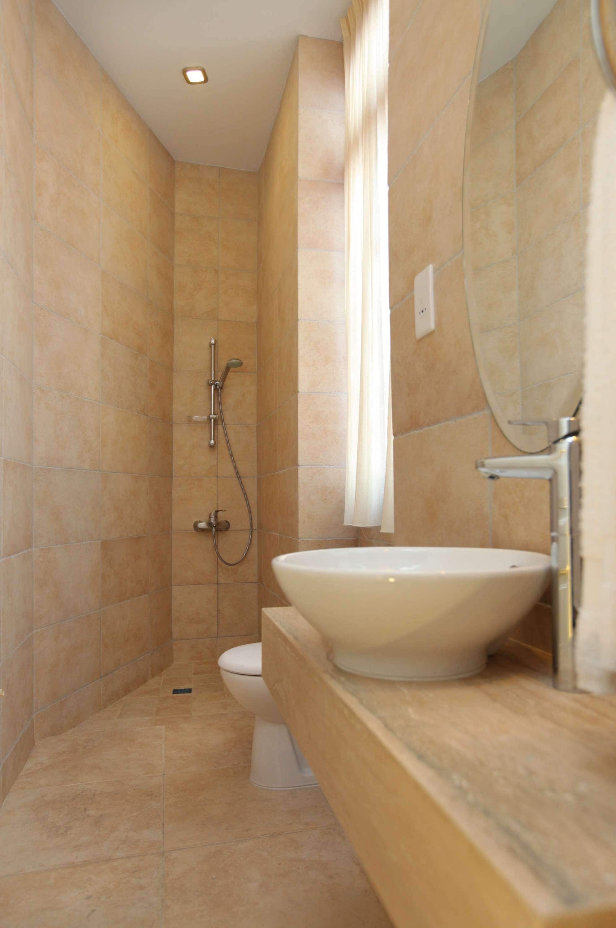 Ein modernes Badezimmer mit einer beige gefliesten Dusche, einem weißen Waschbecken und einem großen Spiegel.