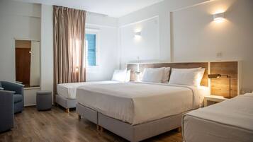 Habitación de hotel moderna con una cama grande, mesitas de noche, zona de estar y una ventana con cortinas.