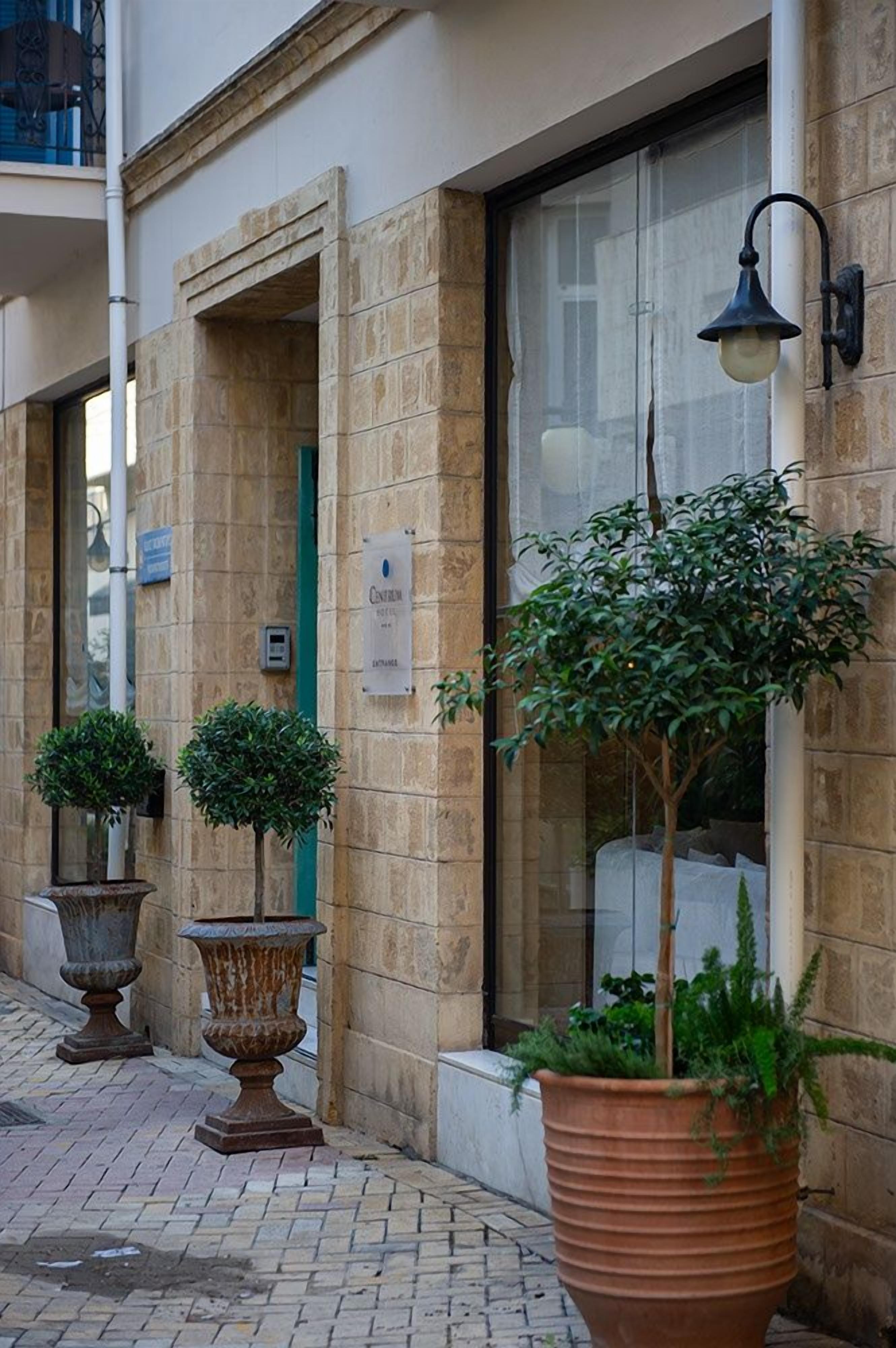 A building facade with a stone wall, a large window, and a sign indicating a hotel entrance.