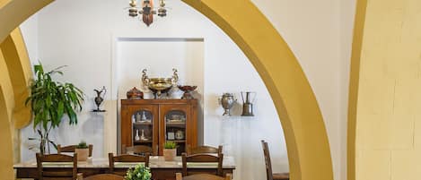 Ein Essbereich mit hoher, gewölbter Decke, einem zentralen Tisch und Stühlen sowie einer darüber hängenden Chandelier.