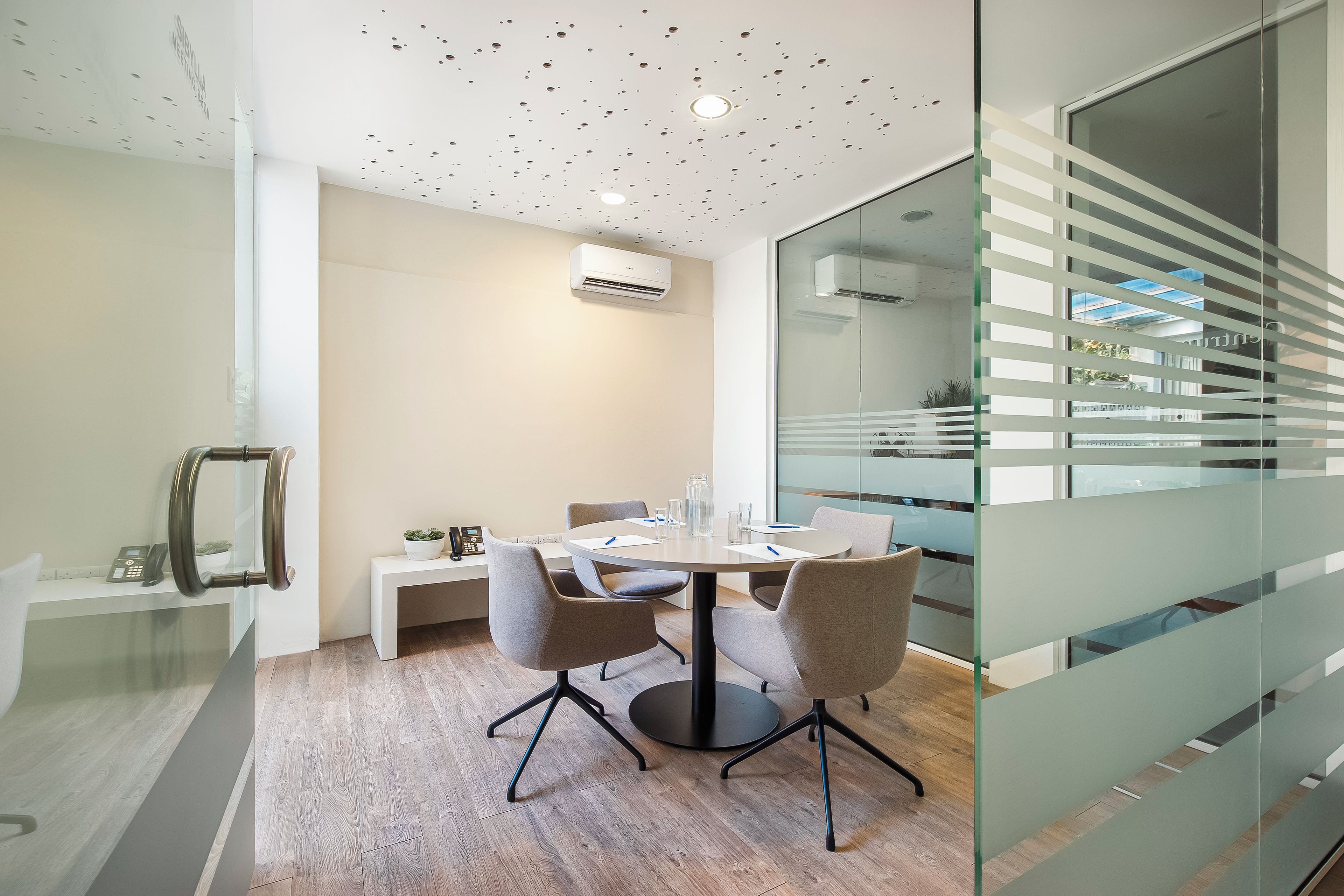 Une salle de conférence moderne dotée d’une cloison en verre, d’une table ronde et de chaises de bureau.