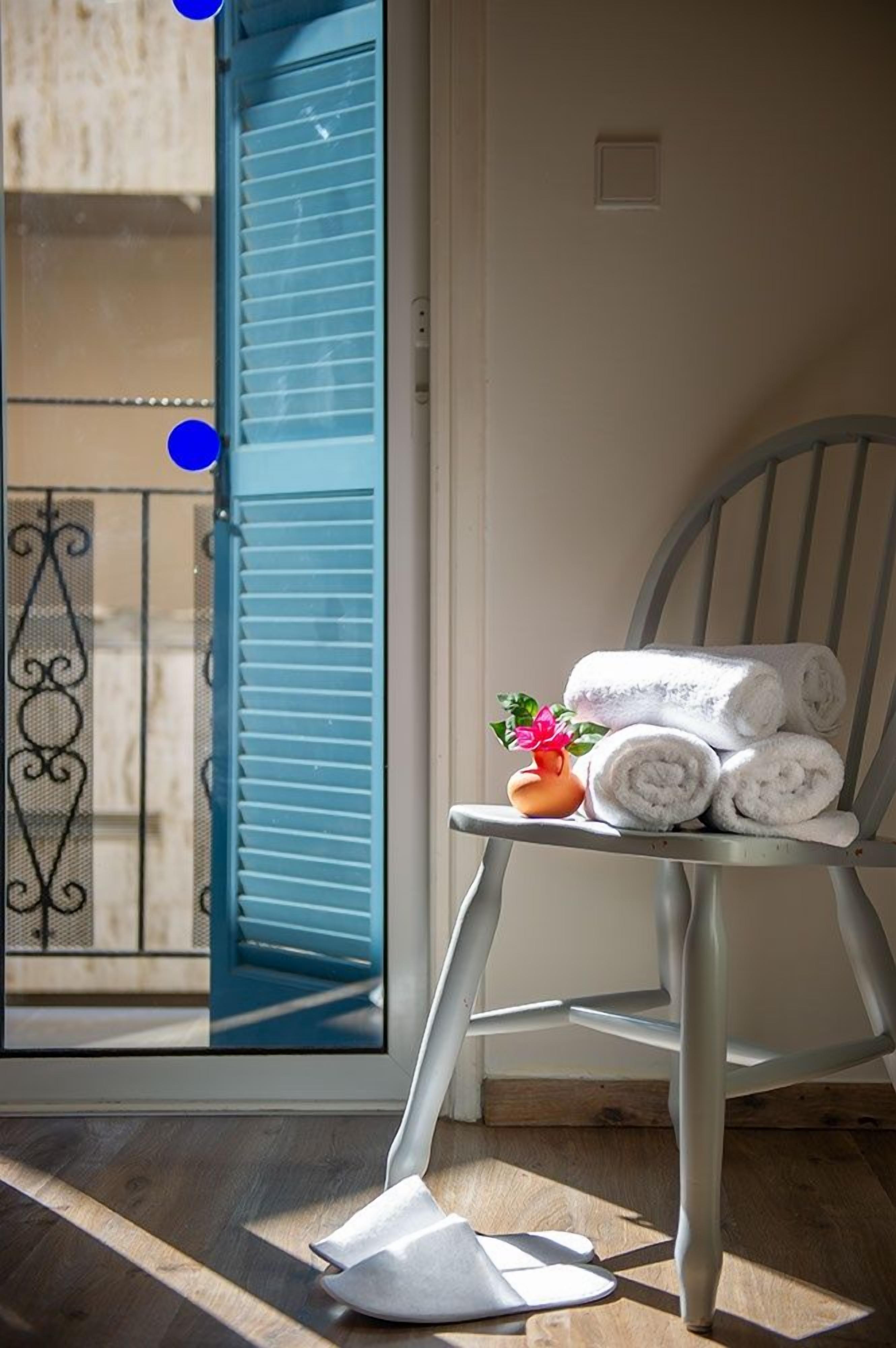 Une pièce avec une chaise, une fenêtre avec des volets bleus et une vue sur le balcon extérieur.