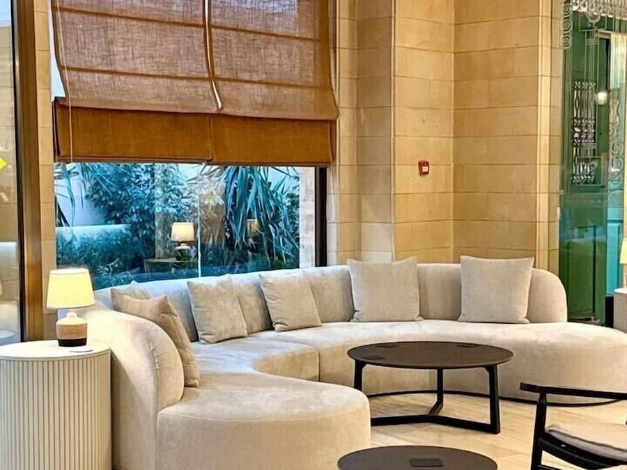 Una sala de estar moderna con un sofá modular, una mesa de centro redonda y una mesita de noche con lámpara.