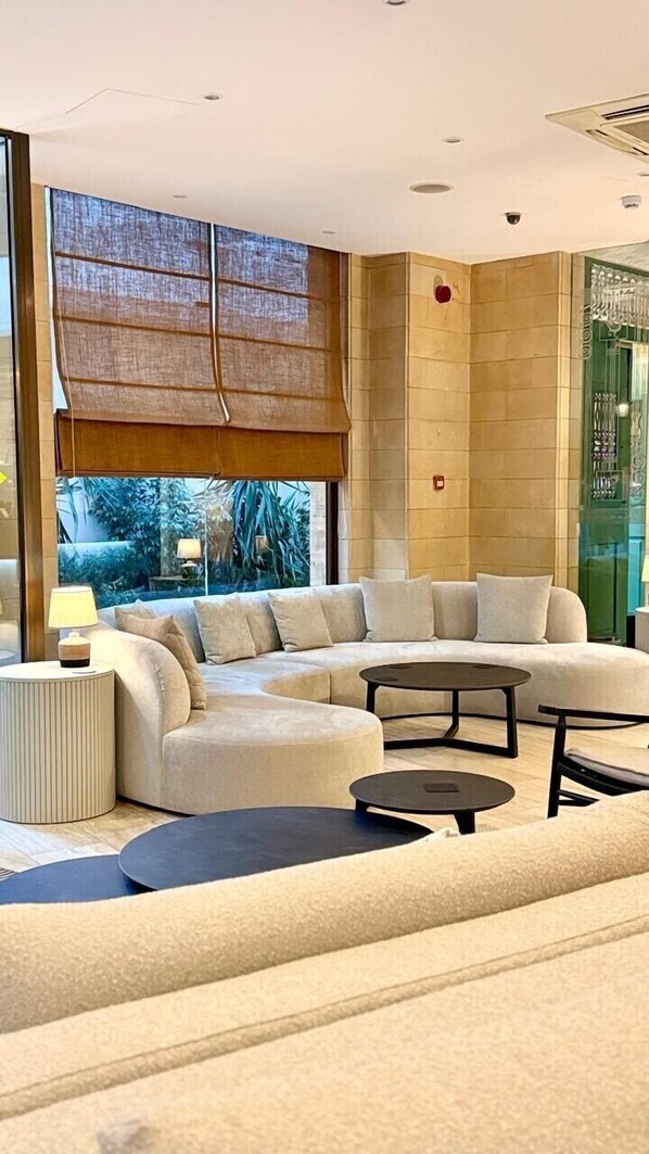 Uma sala de estar moderna com um sofá seccional, uma mesa de centro redonda e uma mesa lateral com abajur.