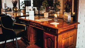 Una zona de bar con barra de madera, una silla de cuero negro, una encimera blanca y varios objetos decorativos, como velas y plantas en macetas.