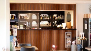 Un área de bar con paneles de madera, estantes llenos de botellas y un refrigerador.