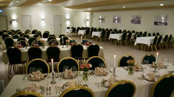 Un salón de banquetes con varias mesas dispuestas para cenar, cada una con sillas y cubiertos.