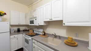 A modern kitchen with white cabinetry, a built-in microwave, and a sink. - Carlisle House (Carlisle)