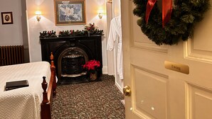 A hotel room with a fireplace, a bed, a chandelier, and a door with a wreath. - Carlisle House (Carlisle)