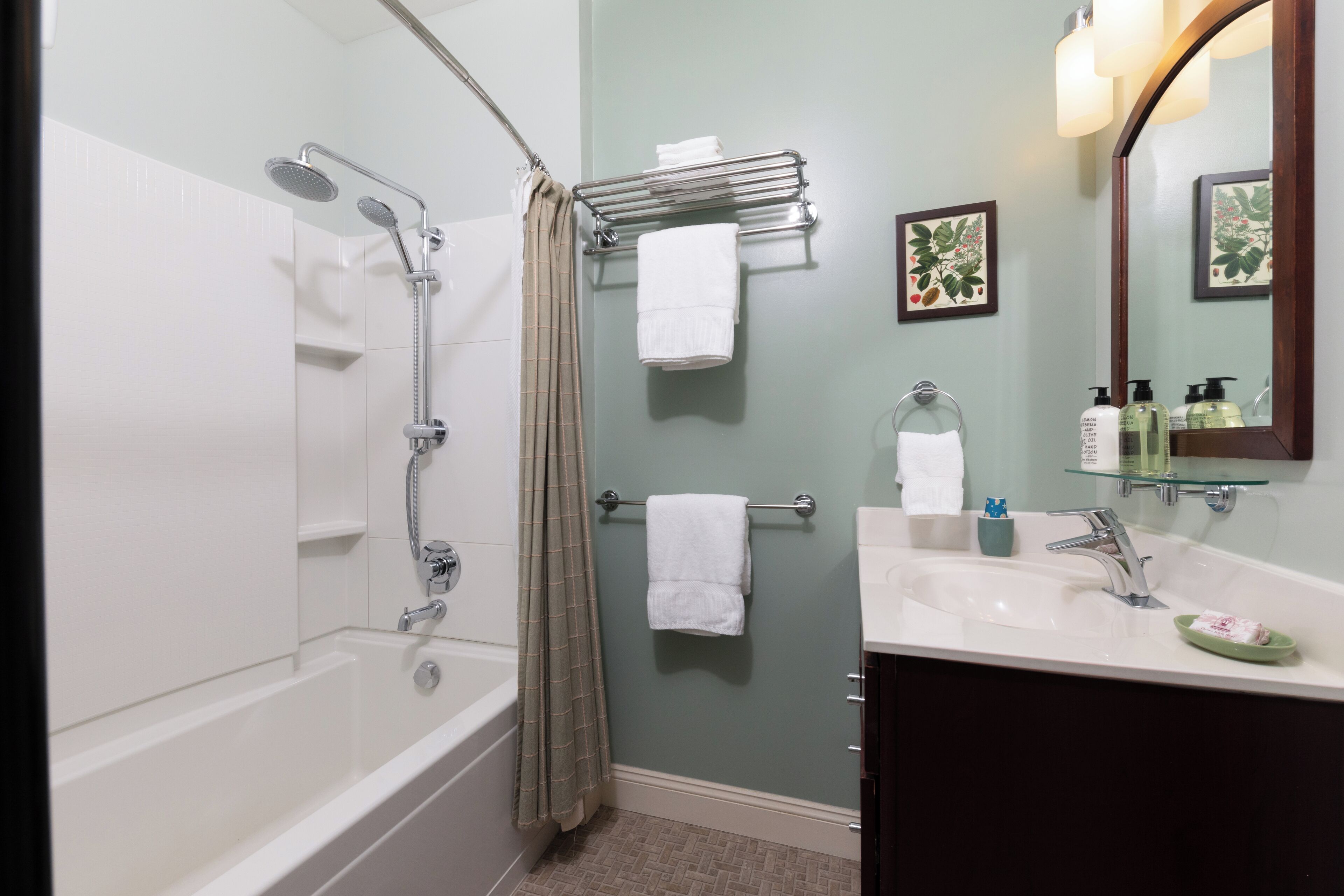 A bathroom with a bathtub, shower, and sink. There are towels and toiletries on the sink.