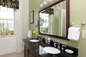 A bathroom with two sinks, a large mirror, and a window with a view of buildings. - Carlisle House (Carlisle)