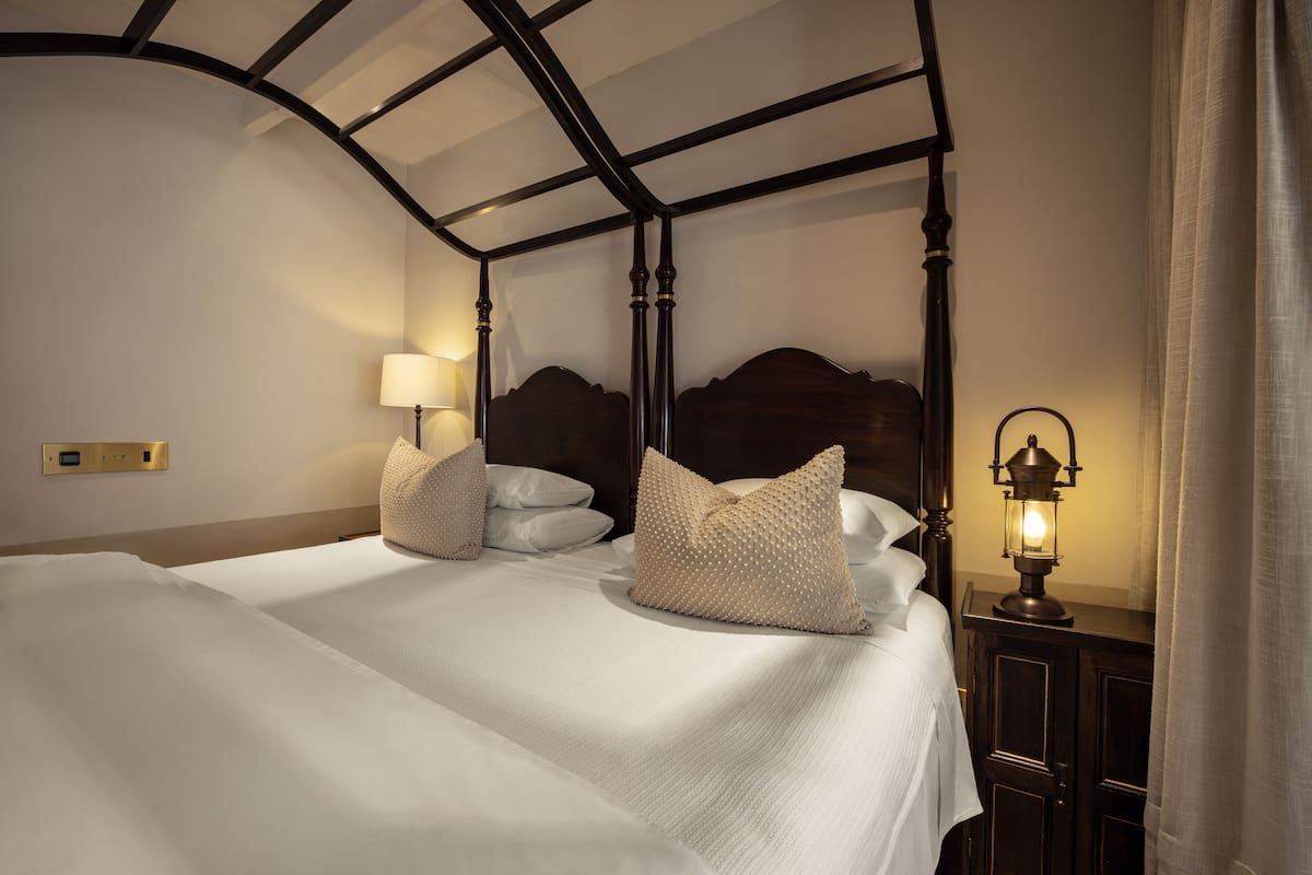 Un lit double avec une tête de lit, deux lampes de chevet et un panneau de commande fixé au mur.