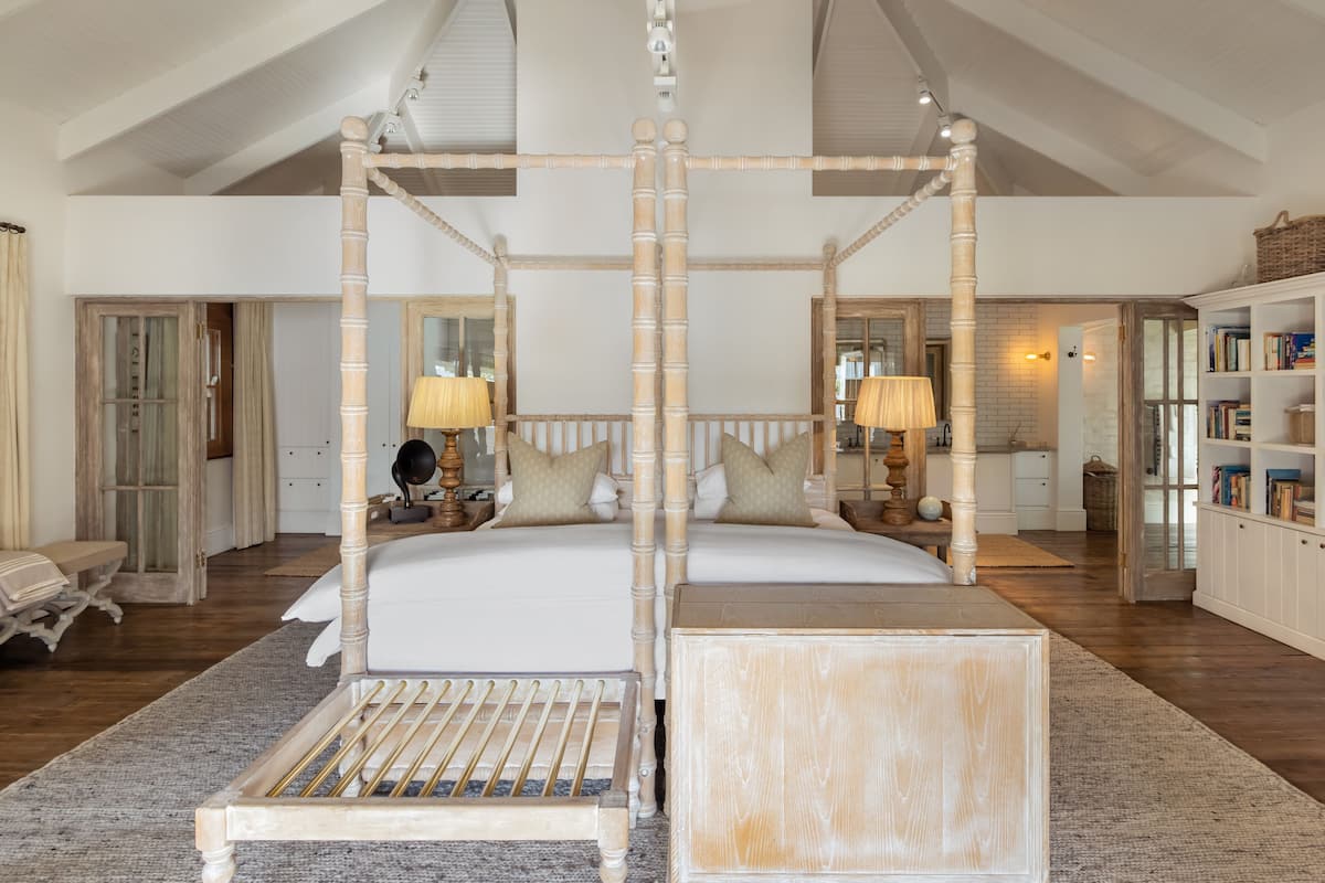 Une chambre spacieuse avec un lit à baldaquin, une table de chevet, une petite table et une bibliothèque.
