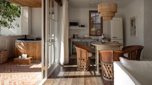 Une cuisine moderne avec un plan de travail en bois, des armoires blanches et un coin repas doté de chaises en osier.
