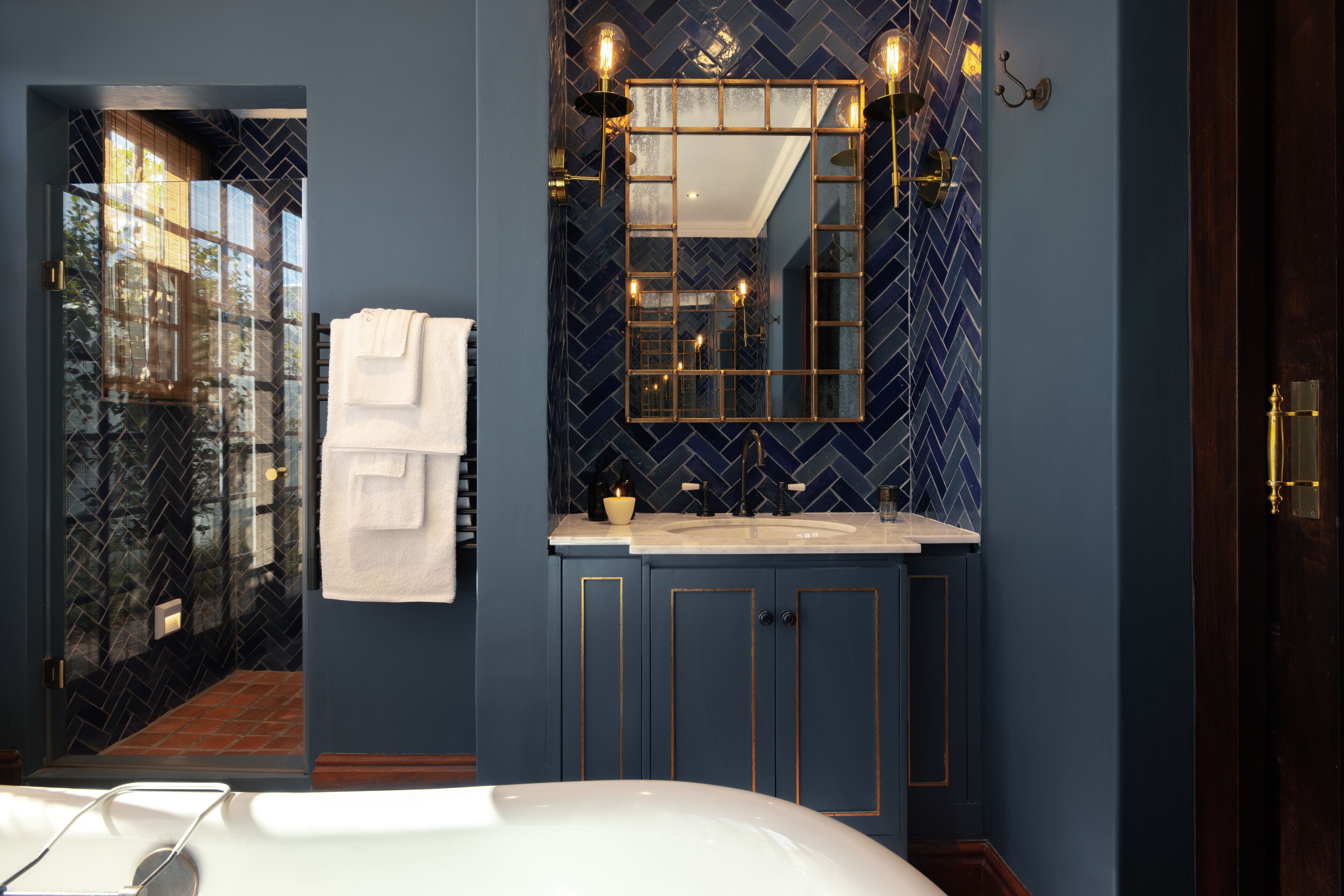 A modern bathroom with a large mirror, a bathtub, and a sink.