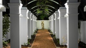 A pathway leading to a statue under a white archway with columns.