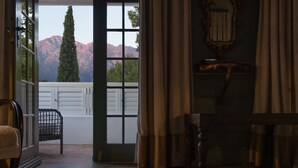 Une pièce avec une vue sur les montagnes, visible à travers une grande fenêtre, comprenant un banc en bois, une chaise et un miroir accroché au mur.