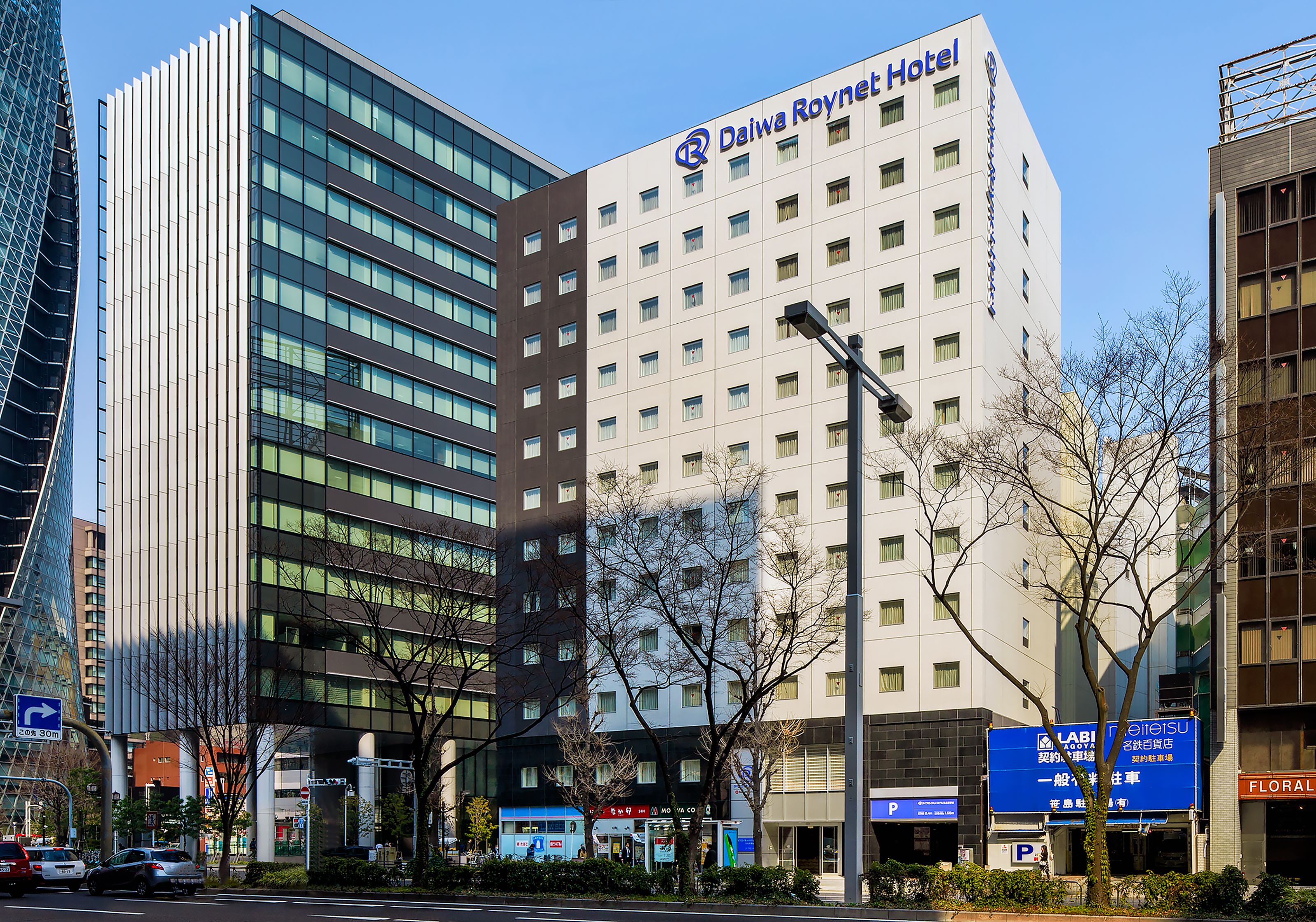 Un hotel moderno con un letrero llamativo, varios pisos y una vista despejada del entorno urbano.