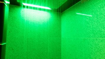 A room with a green-lit ceiling and tiled walls.