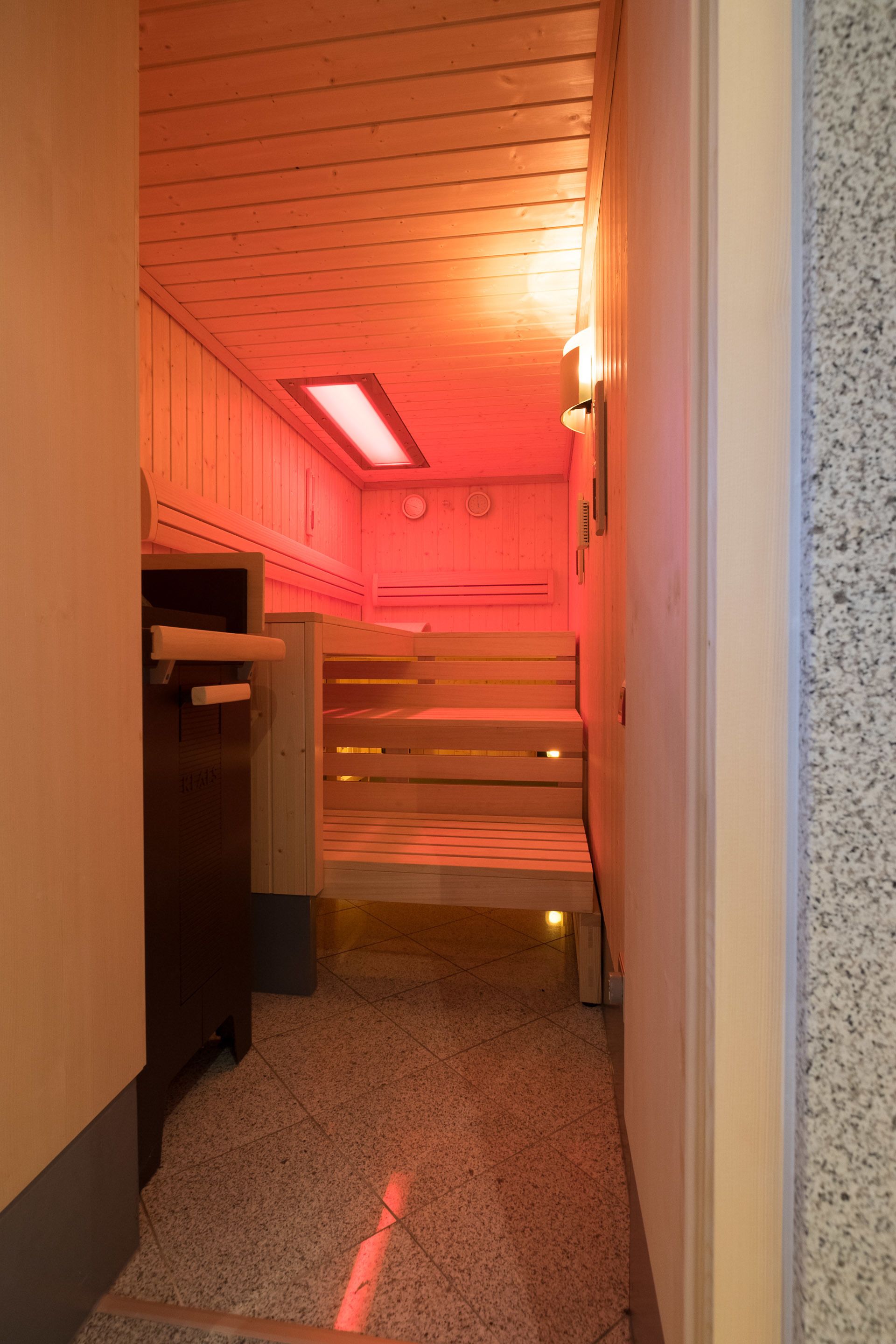 A sauna room with wooden benches and a sloped ceiling.
