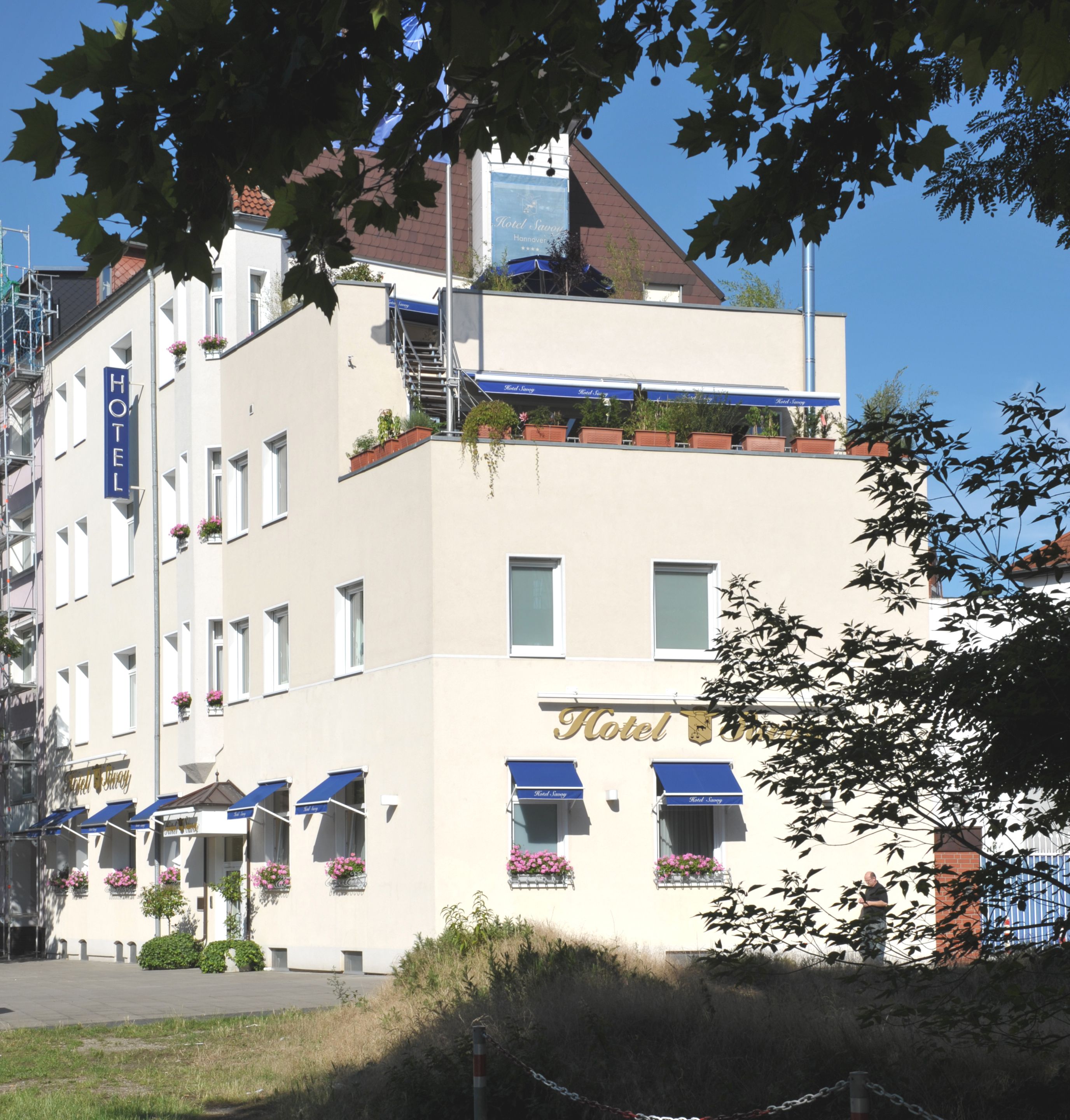 A hotel with a white facade, multiple windows, and balconies with flower boxes.