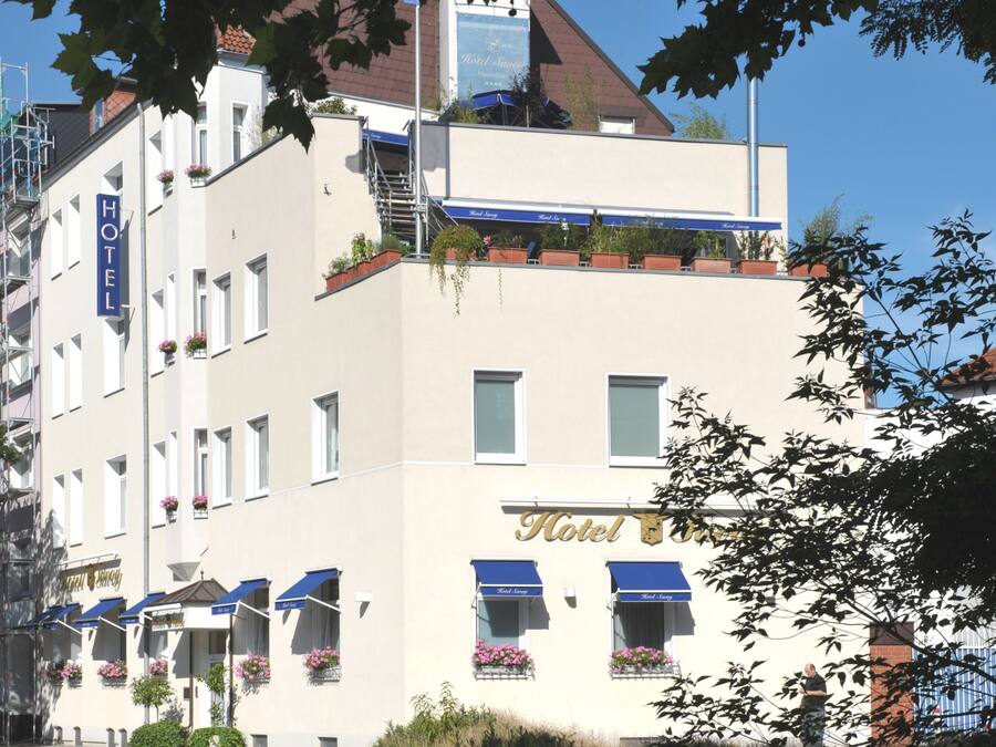 A hotel with a white facade, multiple windows, and balconies with flower boxes.