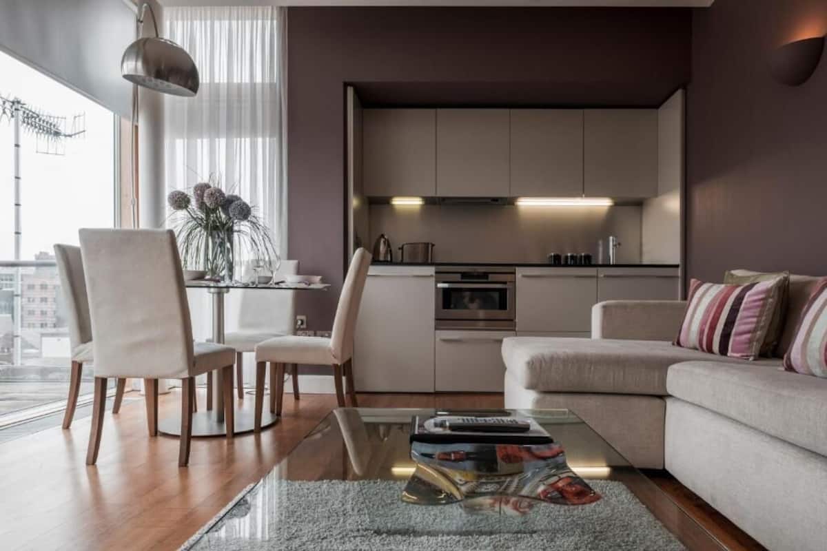 A modern living room with a glass coffee table, a sofa, and a dining area with chairs.
