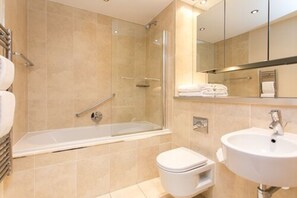 A modern bathroom with a bathtub, toilet, and sink. - The Chambers - Park Place - Apartments (Leeds)