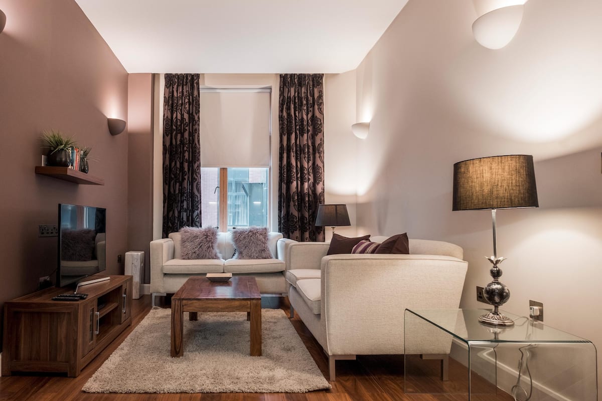 A modern living room with a sofa, coffee table, TV, and lamp.