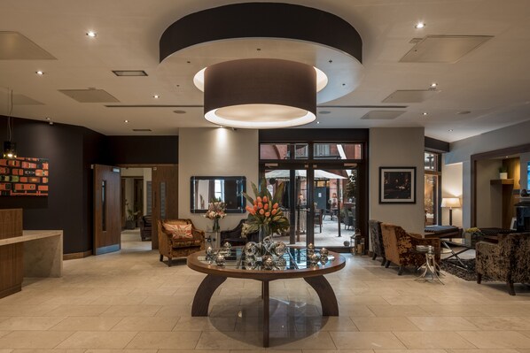 A spacious lobby with a central round table, modern lighting, and comfortable seating areas. - The Chambers - Park Place - Apartments (Leeds)